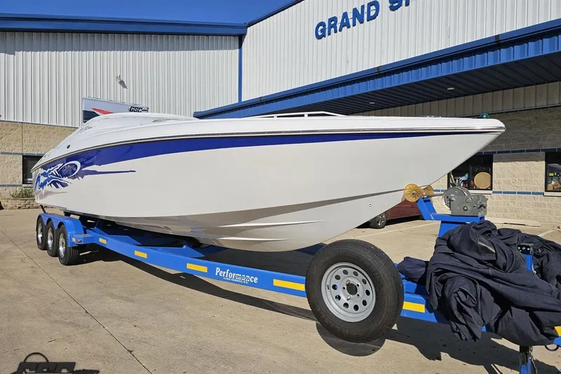 Slide: The Image of 2004 Baja 29 Outlaw boat on a blue trailer outside a showroom. - 12
