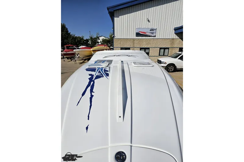 Slide: The Image of 2004 Baja 29 Outlaw boat with sleek design and blue graphics, parked outdoors. - 15