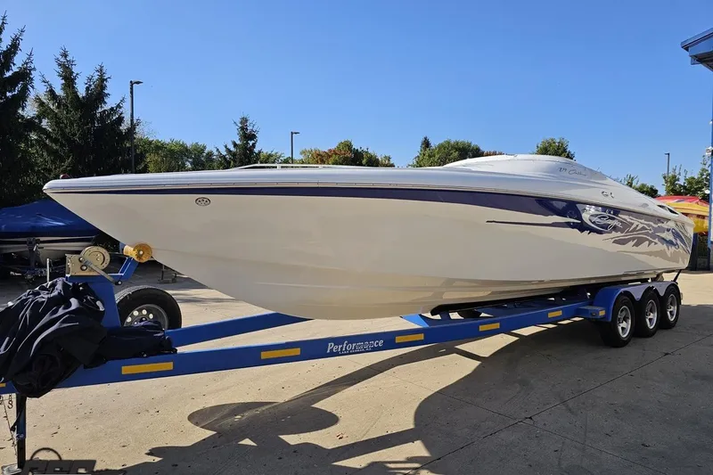 Slide: The Image of 2004 Baja 29 Outlaw speedboat on a blue trailer, parked outdoors. - 16