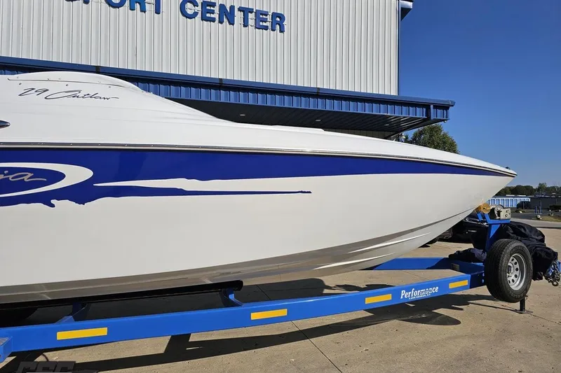 Slide: The Image of 2004 Baja 29 Outlaw boat on blue trailer outside a sport center. - 4