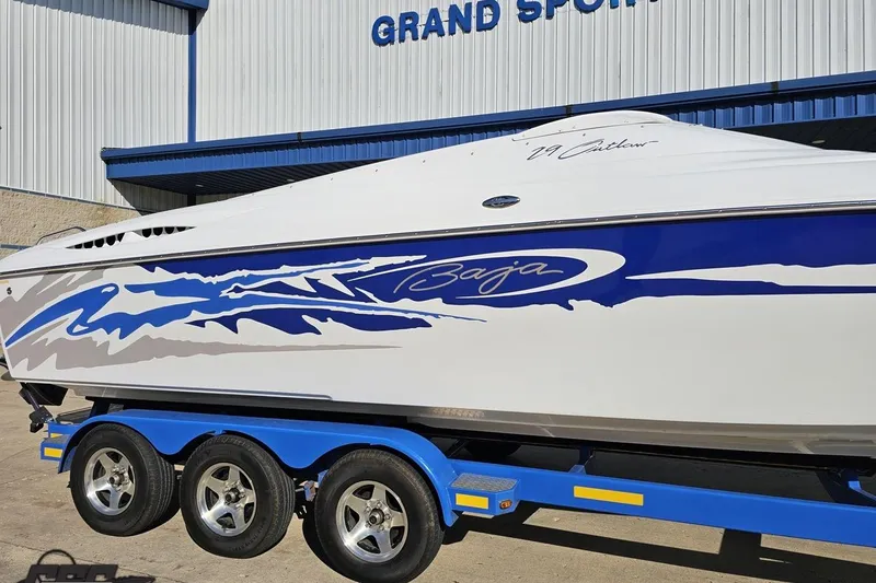Slide: The Image of 2004 Baja 29 Outlaw boat with blue graphics on a trailer outside a building. - 5