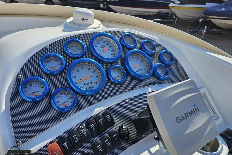 Slide: The Image of Dashboard of a 2004 Baja 29 Outlaw boat with blue-rimmed gauges and Garmin device. - 54