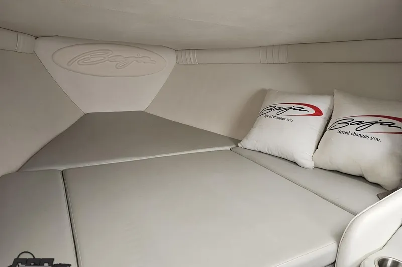 Slide: The Image of 2004 Baja 29 Outlaw cabin interior with branded pillows and sleek white upholstery. - 63