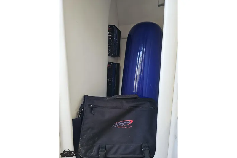 Slide: The Image of Storage compartment in a 2004 Baja 29 Outlaw boat with a blue tank and black bag. - 68