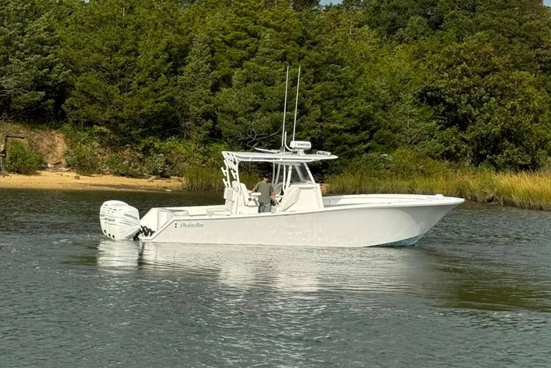 Slide: The Image of 2019 Onslow Bay 33 Tournament boat on calm water near a wooded shoreline. - 18