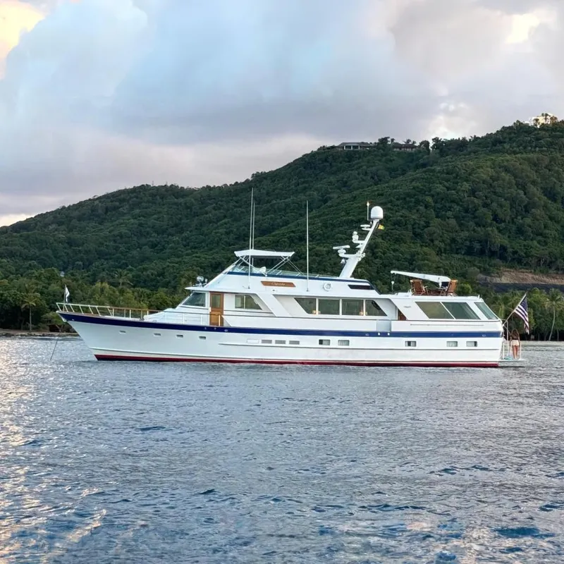 The Image of 1987 Burger Motoryacht anchored near lush green hills and calm waters. - 0