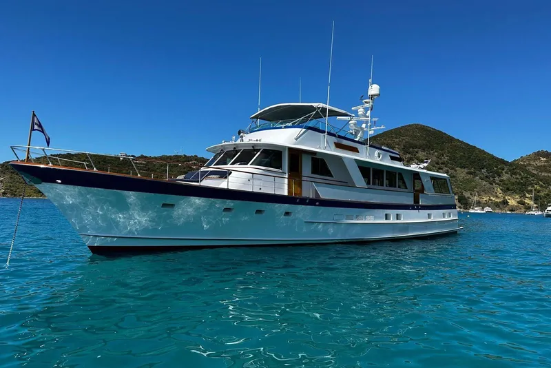 Slide: The Image of 1987 Burger Motoryacht on clear blue water with scenic hillside background. - 2