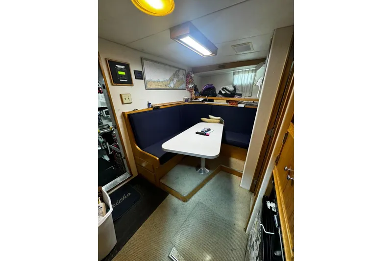 Slide: The Image of Interior of a 1987 Burger Motoryacht with a cozy dining area and blue seating. - 23