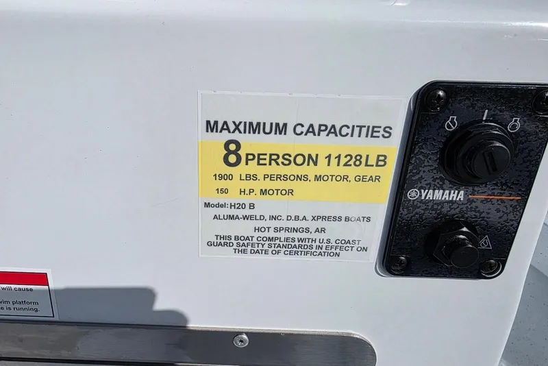 Slide: The Image of 2026 Xpress H20B Bay boat capacity label, 8 persons, 1128 lbs, 150 HP motor. - 22