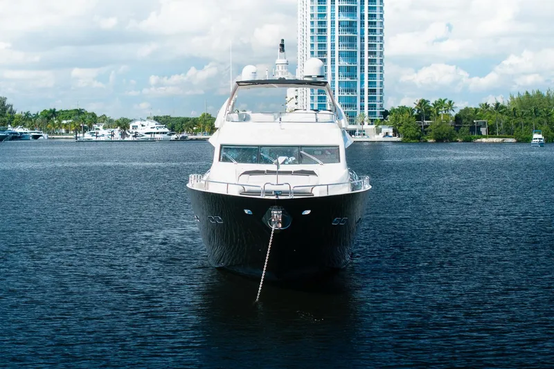 Slide: The Image of Front view of a 2008 Sunseeker 90 Yacht on calm water, with a cityscape backdrop. - 13