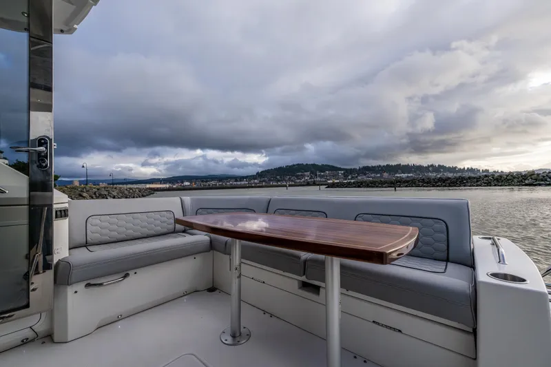 Slide: The Image of 2014 Cruisers Yachts 45 Cantius cockpit with seating and table, overlooking scenic waterfront. - 16