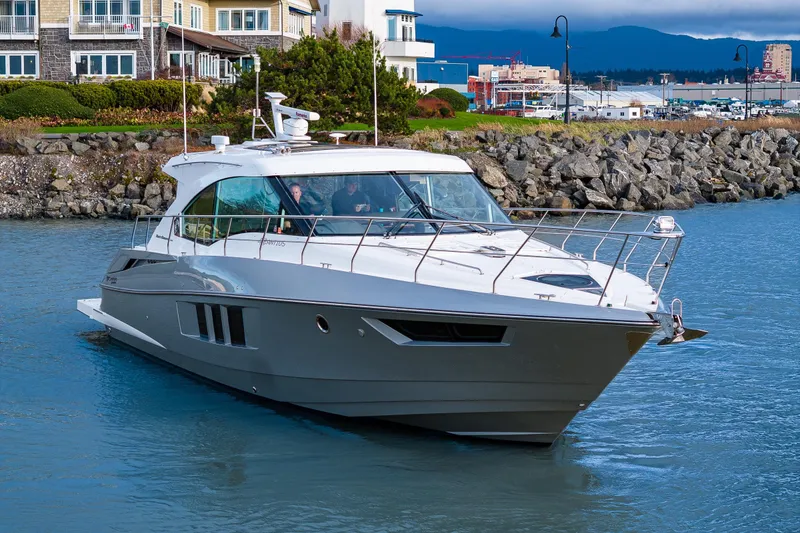 Slide: The Image of 2014 Cruisers Yachts 45 Cantius navigating near rocky shoreline and waterfront homes. - 11
