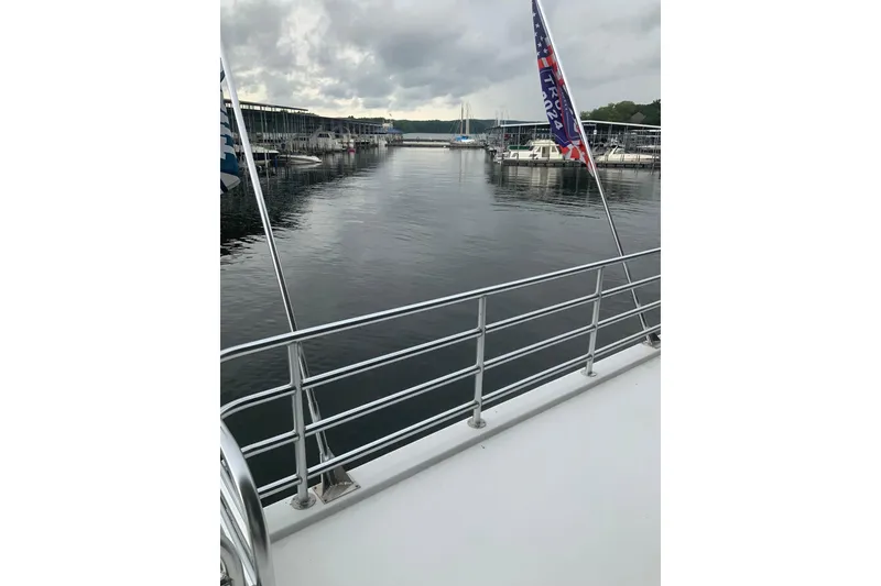 Slide: The Image of 2023 Sumerset 18 x 81 houseboat docked at a marina with flags. - 27