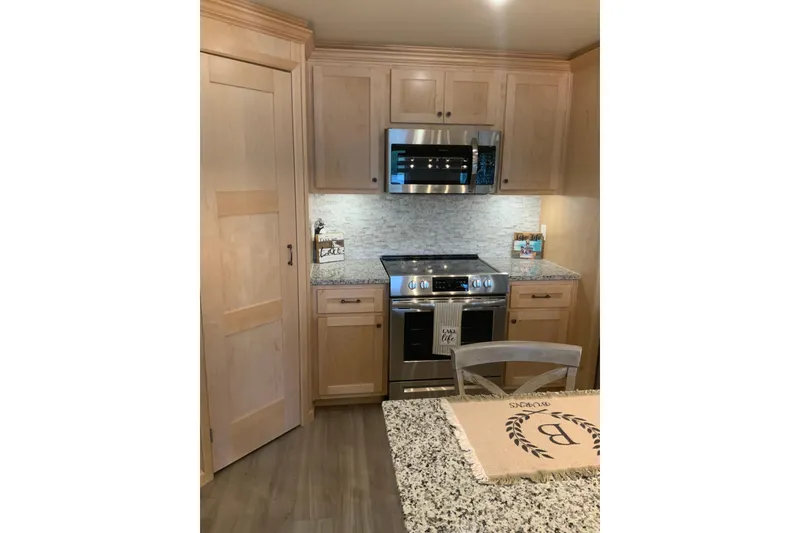 Slide: The Image of Modern kitchen in 2023 Sumerset 18 x 81 houseboat with granite countertops and wooden cabinets. - 46