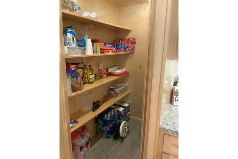 Slide: The Image of Pantry shelves stocked with food and supplies in a 2023 Sumerset 18 x 81 houseboat. - 47