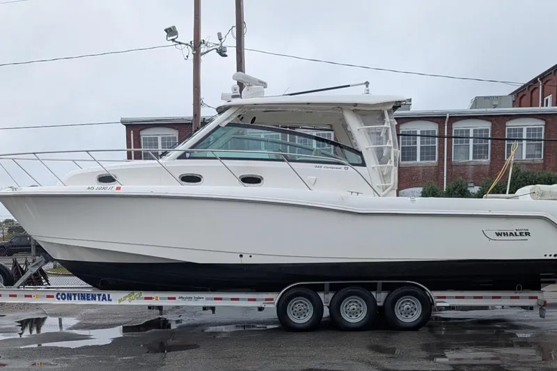 Slide: The Image of 2018 Boston Whaler 245 Conquest boat on trailer, parked outdoors. - 2