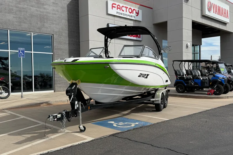 Slide: The Image of 2022 Yamaha Boats 212XD in green and white, displayed at a dealership. - 0