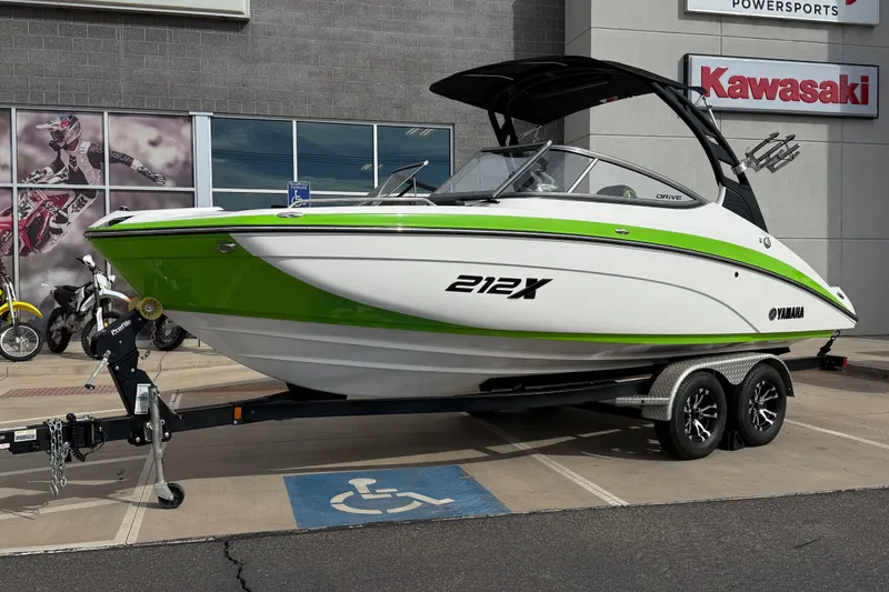 Slide: The Image of 2022 Yamaha Boats 212XD in green and white on trailer, parked outside dealership. - 1
