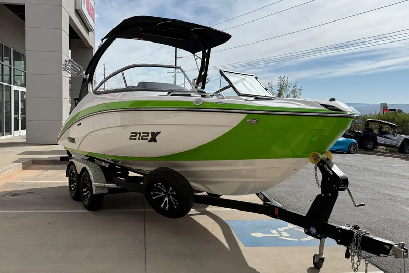 Slide: The Image of 2022 Yamaha Boats 212XD in green and white on a trailer outside a dealership. - 10