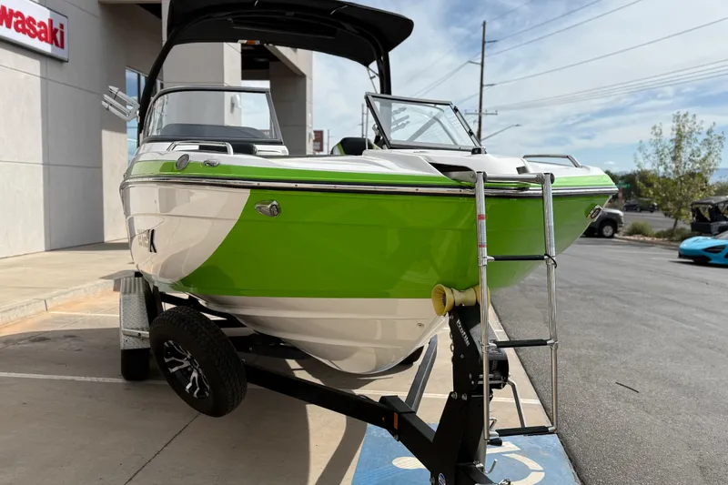 Slide: The Image of 2022 Yamaha Boats 212XD in vibrant green, parked on a trailer outside a dealership. - 12