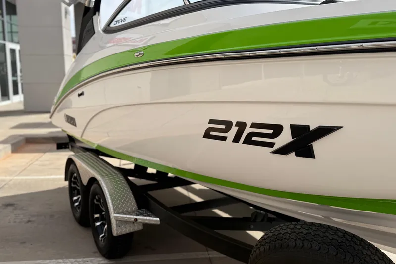 Slide: The Image of 2022 Yamaha Boats 212XD with green accents on a trailer, side view. - 13