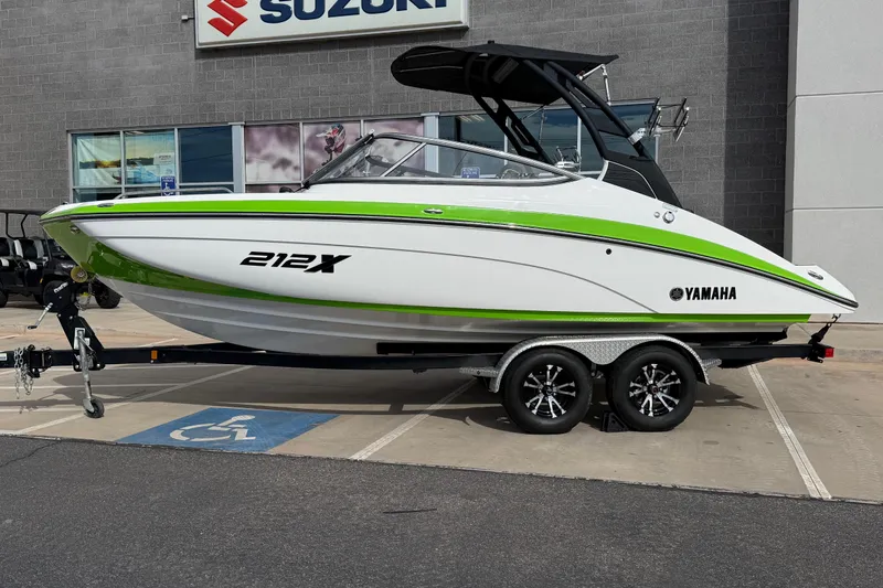 Slide: The Image of 2022 Yamaha Boats 212XD in green and white, displayed on a trailer outside a dealership. - 2