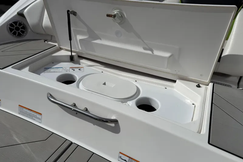 Slide: The Image of Open storage compartment on 2022 Yamaha Boats 212XD, featuring cup holders and sleek design. - 23