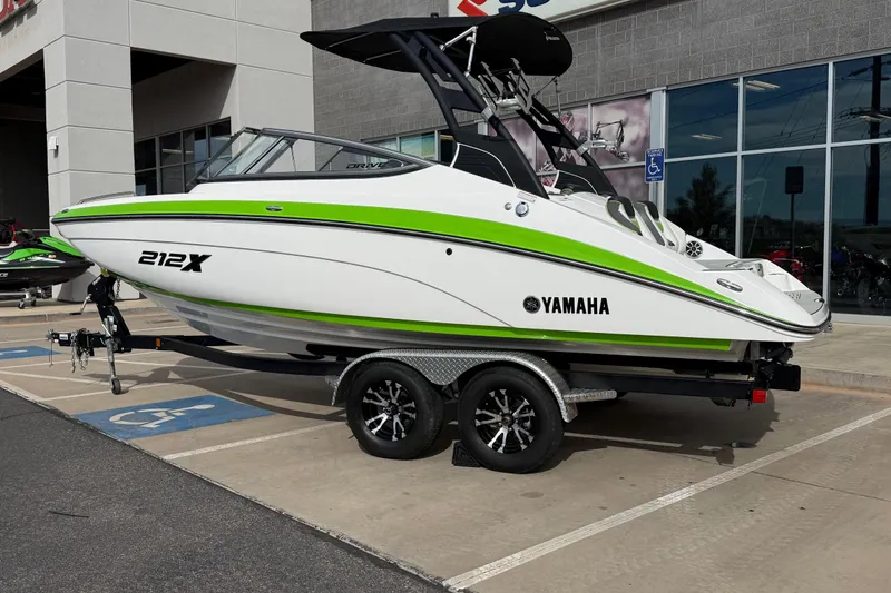 Slide: The Image of 2022 Yamaha Boats 212XD in white and green, parked on a trailer outside a showroom. - 3