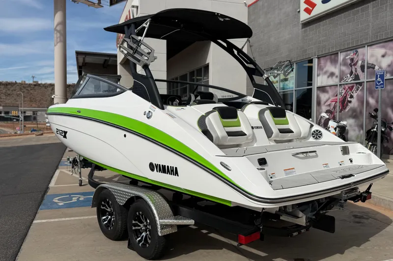 Slide: The Image of 2022 Yamaha Boats 212XD in showroom, white with green accents, on a trailer. - 4