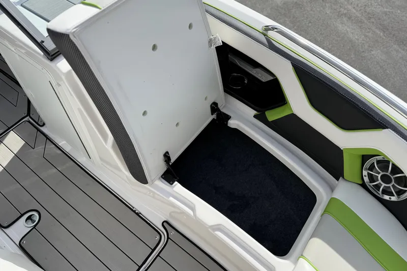 Slide: The Image of 2022 Yamaha Boats 212XD interior storage compartment with green accents and speaker. - 52