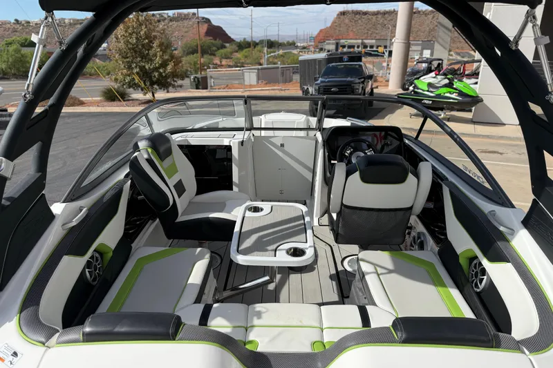 Slide: The Image of 2022 Yamaha Boats 212XD interior with seating, steering wheel, and table, parked outdoors. - 57