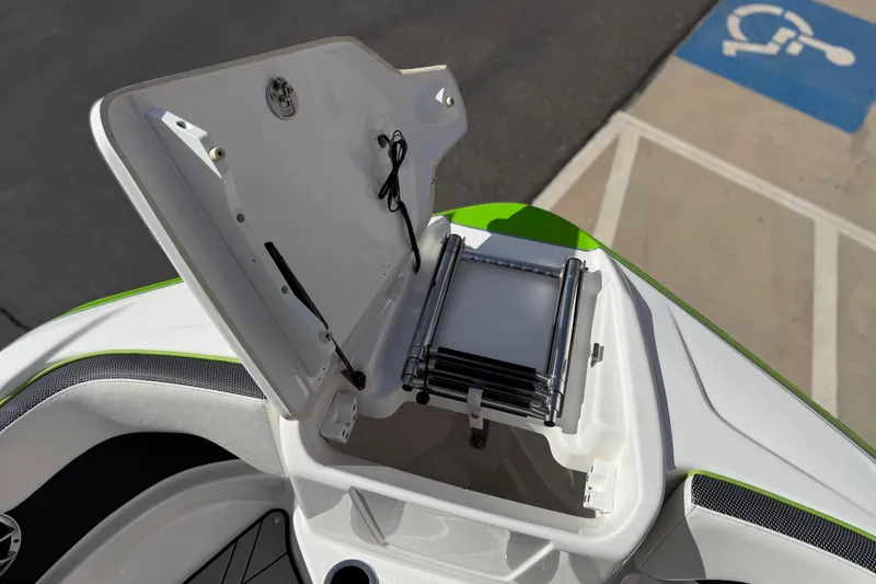 Slide: The Image of 2022 Yamaha Boats 212XD bow storage compartment with ladder, open lid, and green accents. - 61