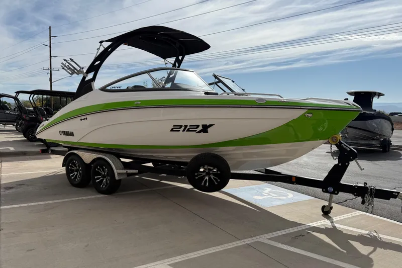 Slide: The Image of 2022 Yamaha Boats 212XD in green and white on a trailer, parked outdoors. - 9