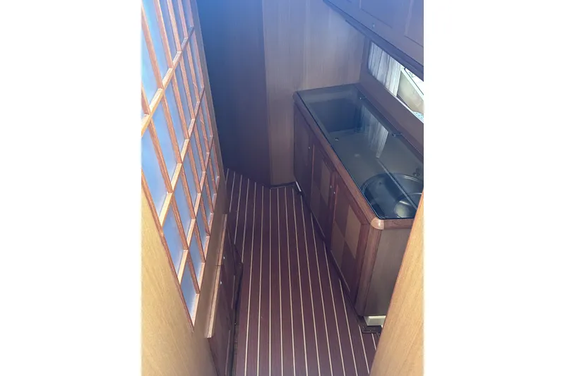 Slide: The Image of 2007 Mochi Craft 44 Dolphin yacht interior with wooden cabinetry and striped flooring. - 14