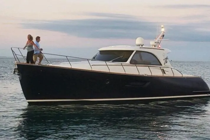 Slide: The Image of 2007 Mochi Craft 44 Dolphin yacht cruising at sunset with two people on deck. - 3