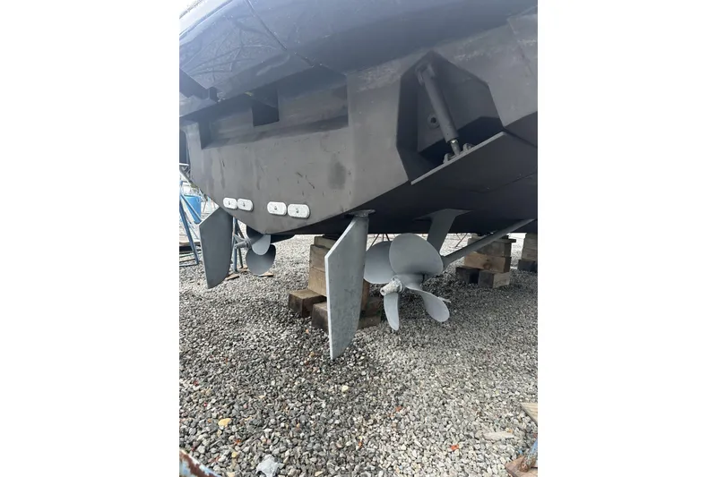 Slide: The Image of 2007 Mochi Craft 44 Dolphin boat propellers and rudders on gravel. - 6