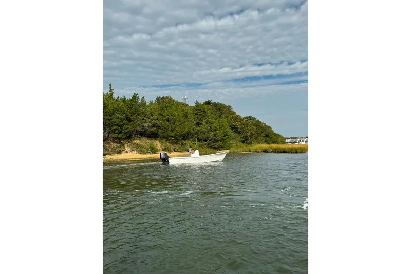 Slide: The Image of 2025 Privateer 20 Roamer boat on calm water near a wooded shoreline. - 17