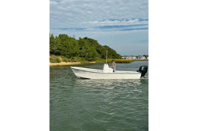 Slide: The Image of 2025 Privateer 20 Roamer boat on calm water near lush shoreline. - 20