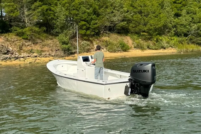 Slide: The Image of 2025 Privateer 20 Roamer boat with Suzuki engine cruising near a wooded shoreline. - 22