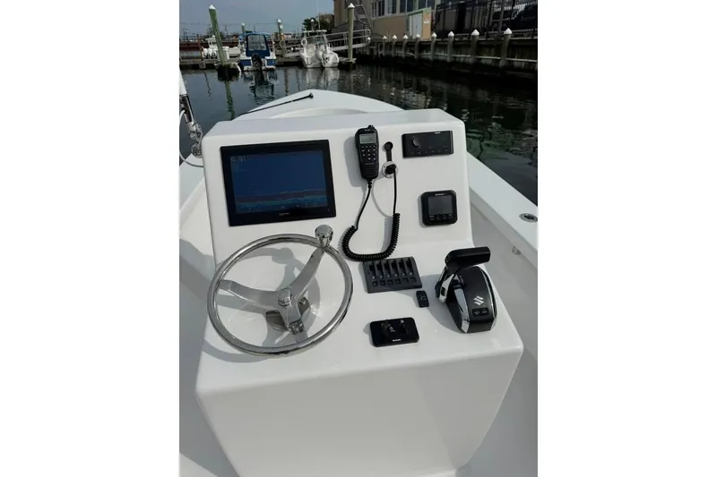 Slide: The Image of 2025 Privateer 20 Roamer boat console with steering wheel, navigation screen, and controls at marina. - 23
