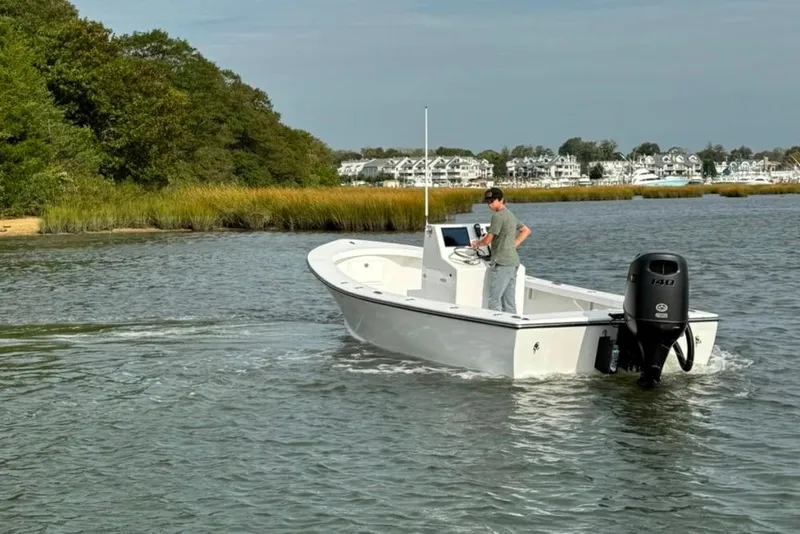 Slide: The Image of 2025 Privateer 20 Roamer boat navigating calm waters near a lush shoreline. - 6