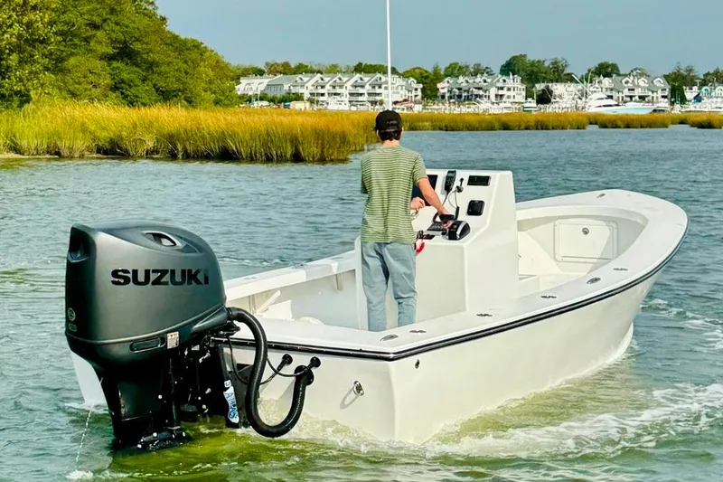 Slide: The Image of 2025 Privateer 20 Roamer boat with Suzuki engine navigating a scenic waterway. - 8