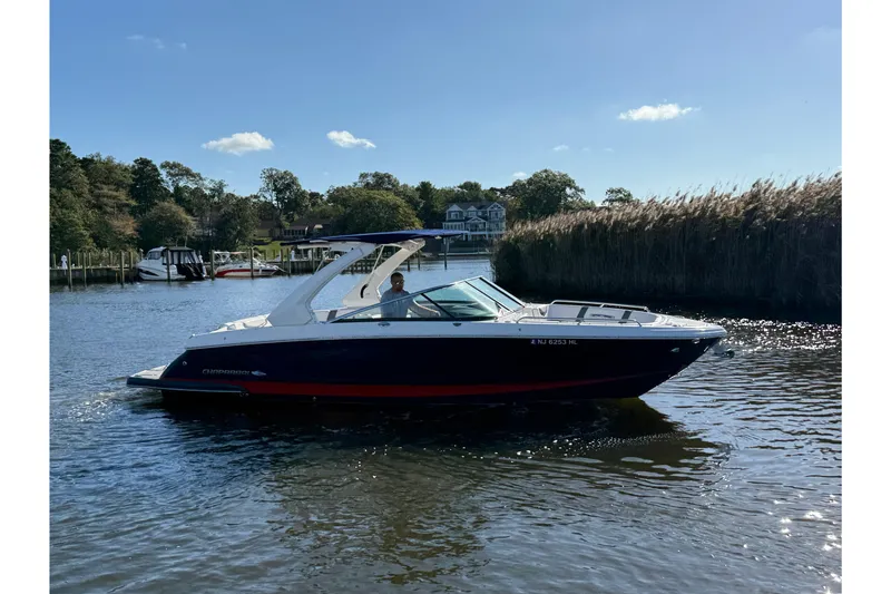 The Image of 2018 Chaparral 287 SSX boat on display, blue hull with red stripe, cloudy sky background. - 0