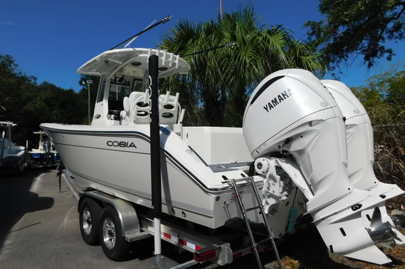 Slide: The Image of 2026 Cobia 285 Center Console boat on trailer, close-up of hull and support bracket. - 50