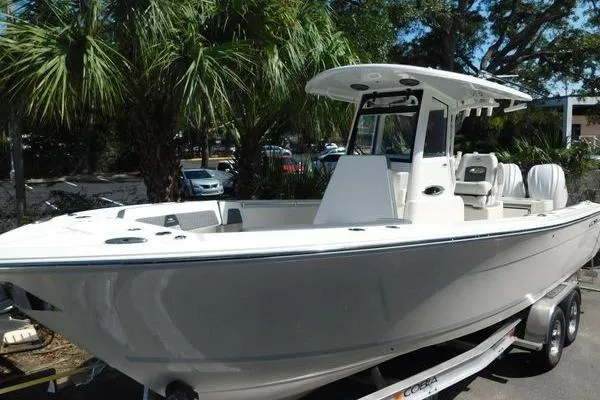 Slide: The Image of 2026 Cobia 285 Center Console boat on trailer, surrounded by palm trees. - 60