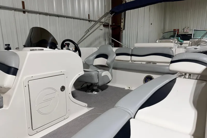 Slide: The Image of 2014 Starcraft 2000 IO Limited boat interior with seating and steering wheel in a storage facility. - 16
