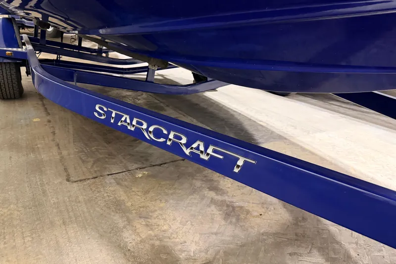 Slide: The Image of Blue 2014 Starcraft 2000 IO Limited boat trailer with logo on concrete floor. - 18