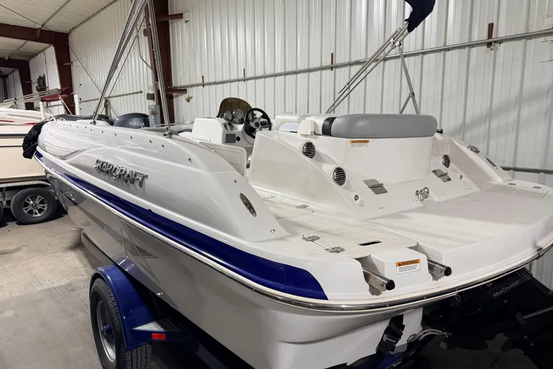 Slide: The Image of 2014 Starcraft 2000 IO Limited boat in indoor storage, featuring sleek white and blue design. - 9
