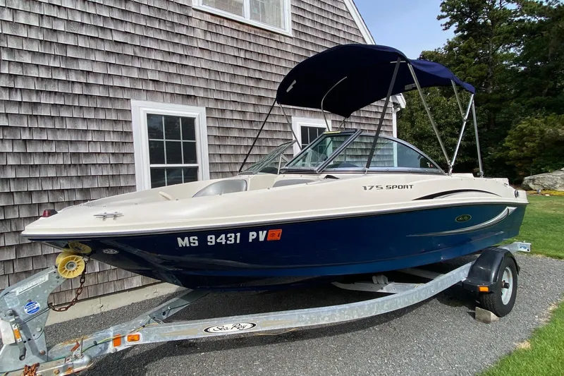 The Image of 2008 Sea Ray 175 Sport boat on trailer, parked beside a shingled building. - 0