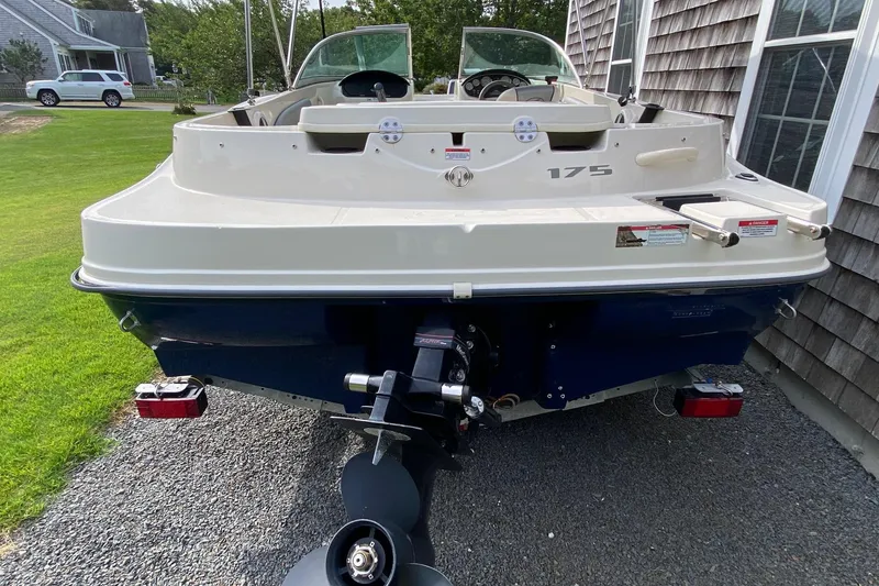 Slide: The Image of 2008 Sea Ray 175 Sport boat, rear view, parked on gravel beside a house. - 2